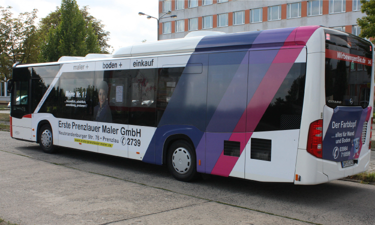 Ein Bus, der mit Werbestickern der Marke Erste Prenzlauer Maler versehen ist.