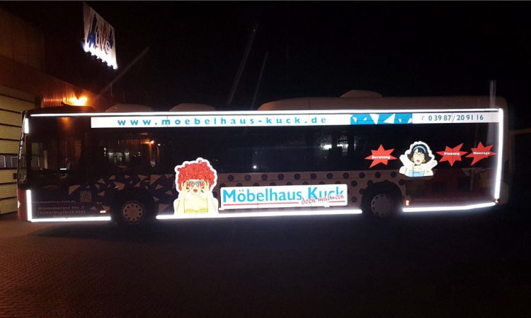 Ein Bus, der mit Werbestickern der Marke Möbelhaus Kuck versehen ist.