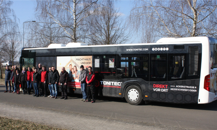 Ein Bus, der mit Werbestickern der Marke ToniTec versehen ist.