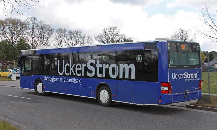 Ein Bus, der mit Werbestickern der Marke UckerStrom versehen ist.