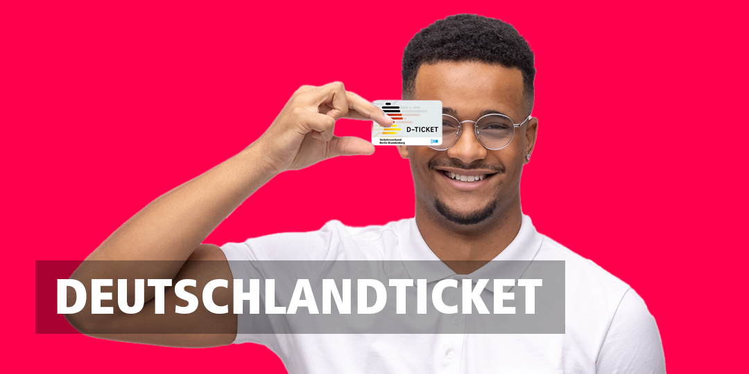 Ein lächelnder Mann hält das Deutschlandticket vor sich hoch.