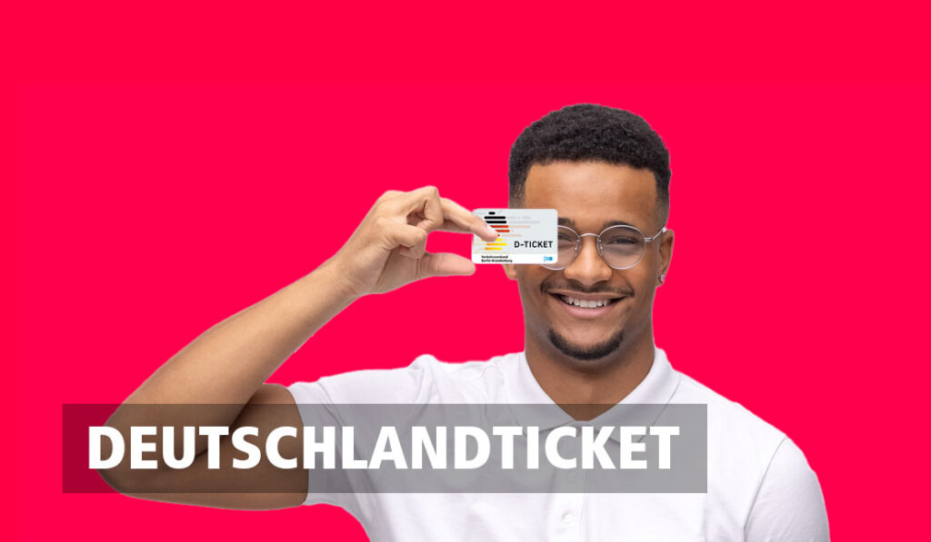 Ein lächelnder Mann hält das Deutschlandticket vor sich hoch. mobile